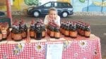 A young boy manning a table loaded with maple syrup at the Karmiel Farmer's Market in Israel